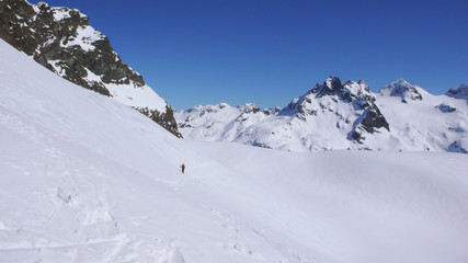 Fototapeta na wymiar backcountry skier hiking along a snow slope on his way to a high alpine mountain peak