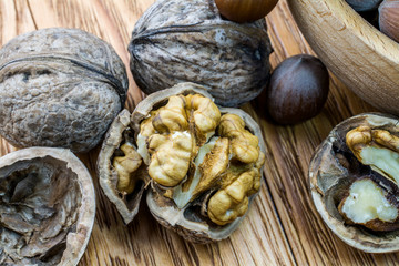 Walnuts and hazelnuts in the split form lie on a wooden background.