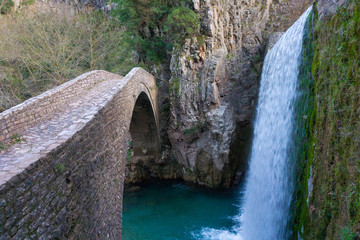 Fototapeta na wymiar Stone arched bridge of Palaiokarya village with its impressive waterfall in Trikala, Greece