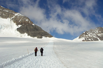 two mountain climbers hiking on a snowy path away from the Jungfraujoch in Switzerland