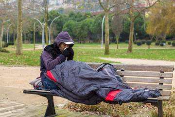 Homeless man is drinking coffee on bench