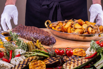A piece of fried meat on a grill with potato in a rural way and mushrooms