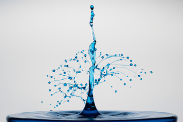 blue waterdrop explosion created by drops crashing into a water pillar