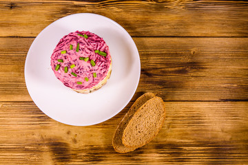 White plate with russian traditional new year salad herring under fur coat and rye bread on wooden table. Top view