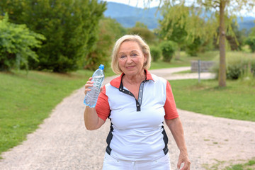 Sporty sweating grandmother drinks water