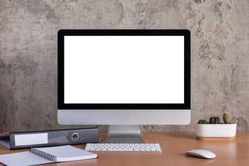 Blank screen of all in one computer with note book, pencil, document file and cactus vase on raw concrete background - obrazy, fototapety, plakaty