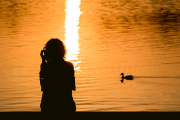 silhouette of young woman on the lake at sunset