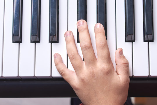  European kid is playing electric piano. He has his music lesson. Close view.