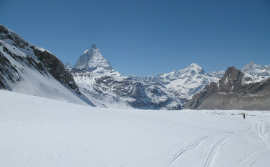 the Monte Rosa mountain range and Matterhorn mountain peak in the Swiss Alps above Zermatt in winter with a backcountry skier in the foreground