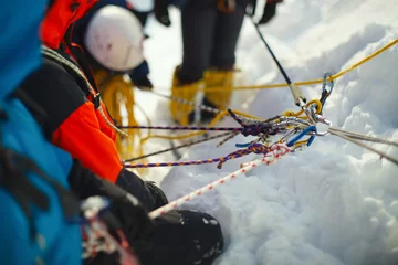 Foto auf Acrylglas Bergsteigen Eine Gruppe von Kletterern an einem verschneiten Berghang, gesichert an einem Sicherungsseil. Kletterstation. Tilt-Shift-Effekt.