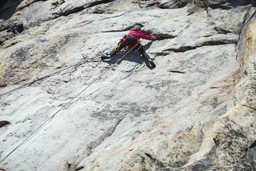 A girl climber climbs up a rock wall. Sports climbing.