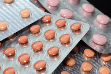 Orange and pink medical tablets in pack, tablets and capsules and tablets packed in blisters. Full screen background. Healthcare and medical concept closeup