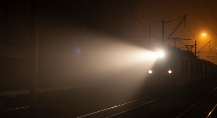 The train arrives at the platform at night. Bright rays of light disperse the darkness