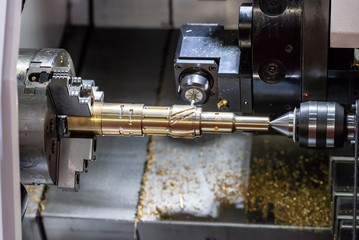 The CNC lathe machine cutting  the slot groove at the brass shaft .Hi-technology automotive part manufacturing process.