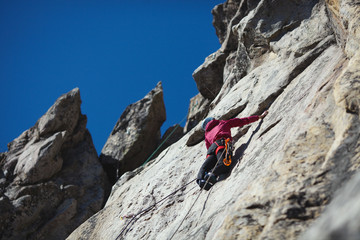 A girl climber climbs up a rock wall. Sports climbing.