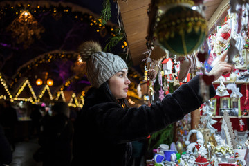 Happy young woman choosing Christmas decoration at market
