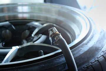 the refill pressure head and black tyre with alloy wheel at car service shop center