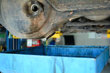 the oil flowing down from the hole to the blue tray between step of Rear gear oil  changing at  the car service shop