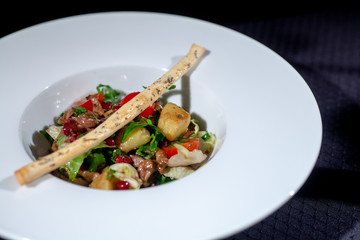 roasted vegetables and beans in a white plate and breadsticks on top