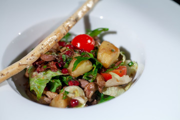 roasted vegetables and beans in a white plate and breadsticks on top