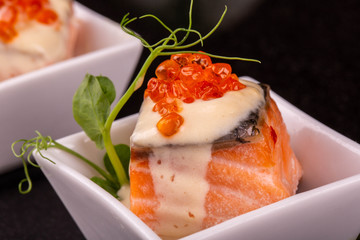A trout in sauce with red caviar and greens