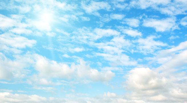 Bright sun on blue sky with clouds. Wide photo .