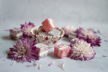 Fleet Ley cubes of fruit marmalade scattered on a white background with purple-colored chrysanthemum flower heads.  Home-made marmalade with chrysanthemum heads on the table