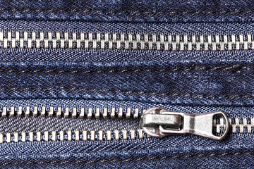 Two metal zippers in jeans trousers. Fashion fabric background texture.