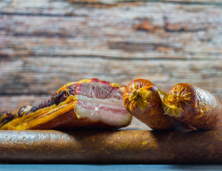 Homemade bacon and sausage on stone background with wood