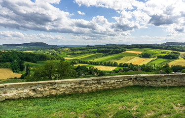 View over agricultural fields, a stone wall and beautiful clouds