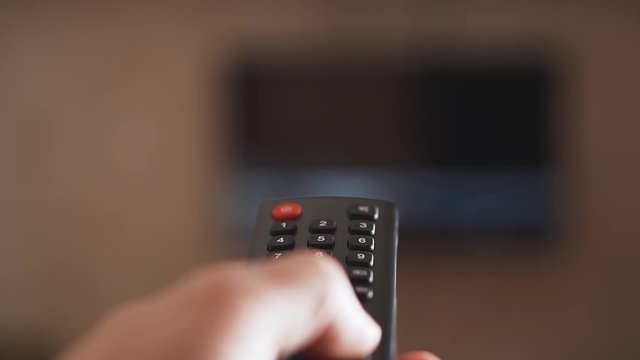 Male hand holding Tv remote control and program switching.