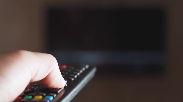 Male hand holding Tv remote control and program switching.
