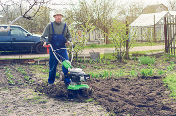 Man working in the spring garden with tiller machine