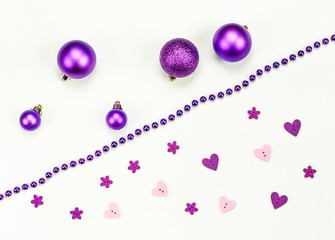 Merry Christmas and Happy New Year composition on white background. New Year decorations in purple and pink colors. New Year`s card.  Five Christmas toys, blue chaplet, pink purple hearts and flowers