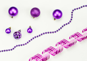 Merry Christmas and Happy New Year composition on white background. New Year decorations in purple and pink colors. New Year`s card.  Six Christmas toys, purple chaplet, pink holiday ribbon