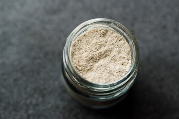 White Pepper Powder in Small Glass Bowl on Grey Granit Surface.