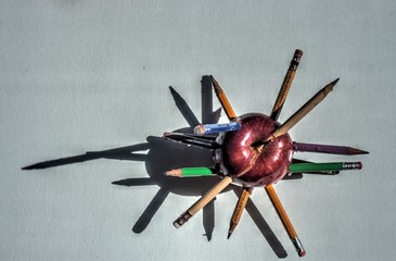 Punctured apple with pencils