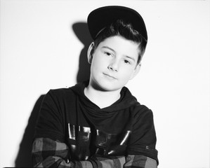 Monochrome studio photo smiling urban boy wearing a baseball cap, jeans and a squared shirt.