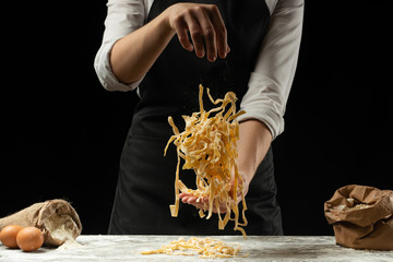 Cooking spaghetti, italian pasta, pasta on a black background. Frost in the air with flour particles. Food banner, large resolution.