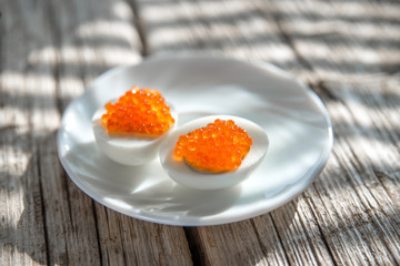 Eggs and salmon caviar on white plate