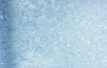 Frozen winter window pane coated shiny icy patterns. Frost background, closeup. Extreme north low temperature. Natural ice glass