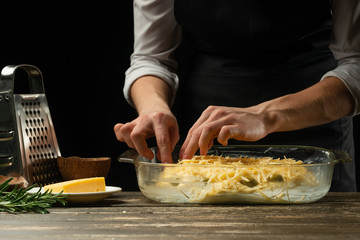 The chef prepares focaccia bread or pizza with olives, butter, cheese and rosemary greens. Recipe for home cooking from the chef. Background for design or menu