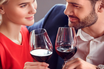 Young couple on date in restaurant sitting drinking wine looking at each other passionate