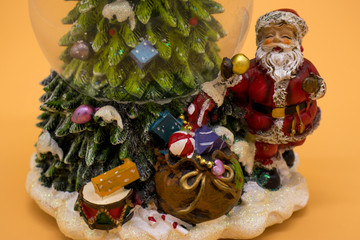 Glass ball with snow along with Santa Claus and gifts