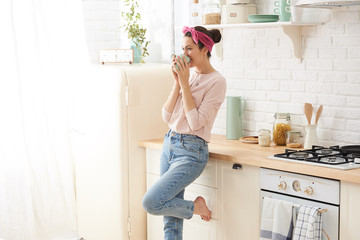 Young woman drinking a morning coffee in kitchen

