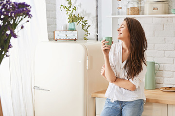 Young woman drinking a morning coffee in kitchen
