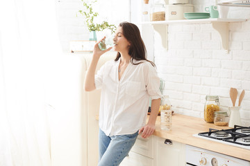 Young woman drinking water from glass in the kitchen