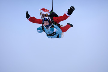 Christmas skydiving. Santa Claus and little girl are in the sky.