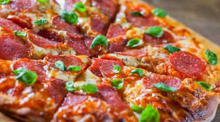 Pepperoni Pizza with Mozzarella cheese, salami, Tomatoes, pepper, Spices and Fresh Basil. Italian pizza on wooden table background