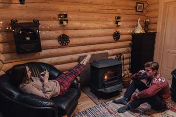 Friends relaxing by the fireplace in log cabin